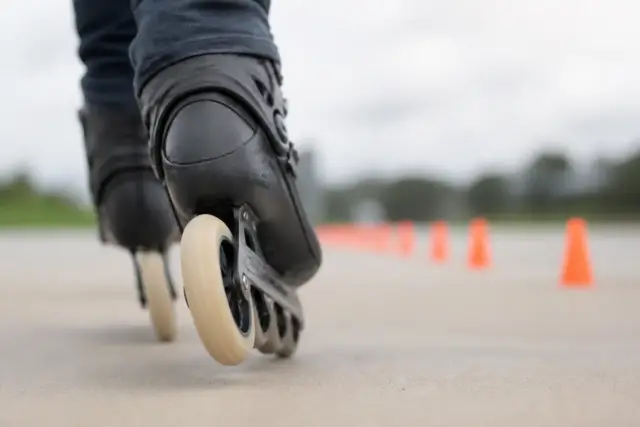 Roue de patin à roulettes immobilisée contre un sol lisse, plots de repère en arrière-plan