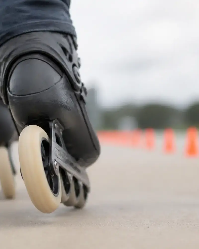 Roue de patin à roulettes immobilisée contre un sol lisse, plots de repère en arrière-plan