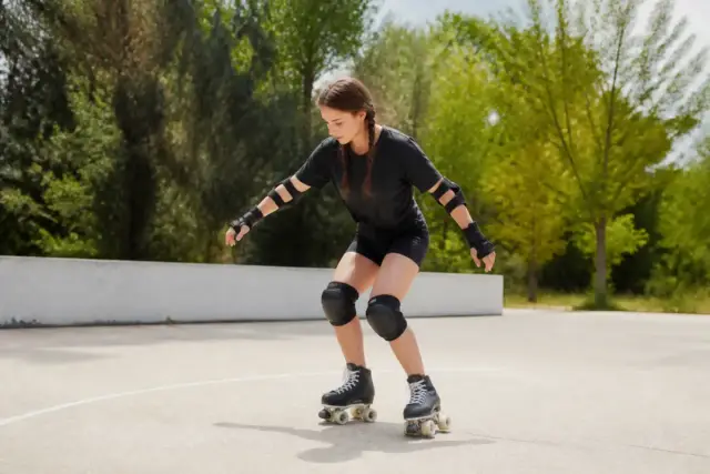 Femme apprenant à faire du roller à 4 roues sur un terrain extérieur sécurisé