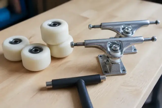 Roues de patin, platine et clé en T posées sur un établi en bois clair, vue rapprochée, lumière douce