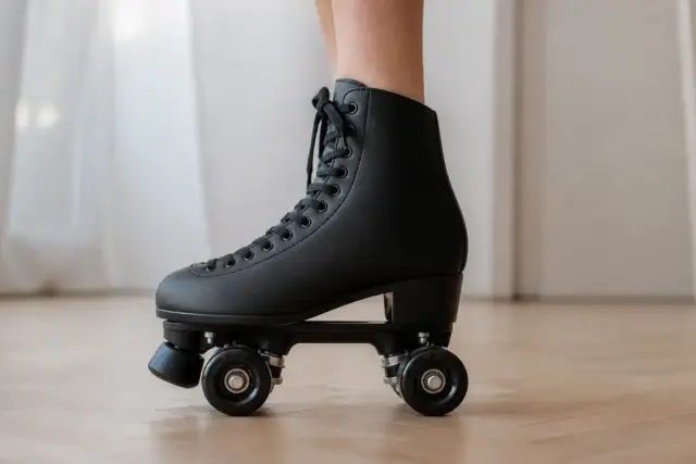 Botte de patin à roulettes montante vue de côté, lacets serrés, fixée sur une platine, sur un parquet clair