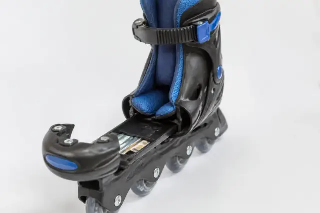 Patin à roulettes pour enfant dont la coque est ouverte à l’avant, montrant le système coulissant de réglage, sur fond clair