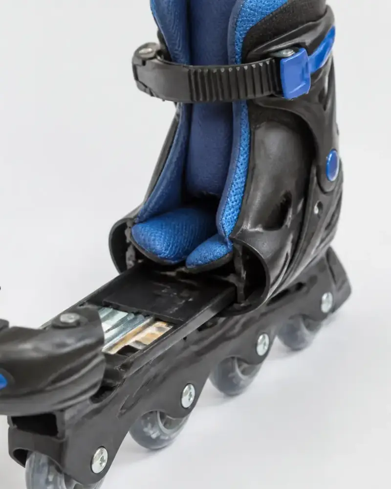 Patin à roulettes pour enfant dont la coque est ouverte à l’avant, montrant le système coulissant de réglage, sur fond clair