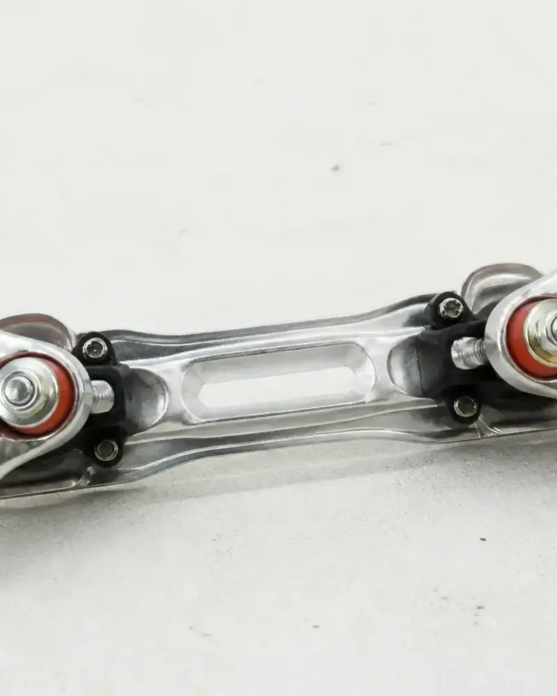 Platine de patin à roulettes vue du dessous sur un fond clair, essieux et gommes visibles, sans roues