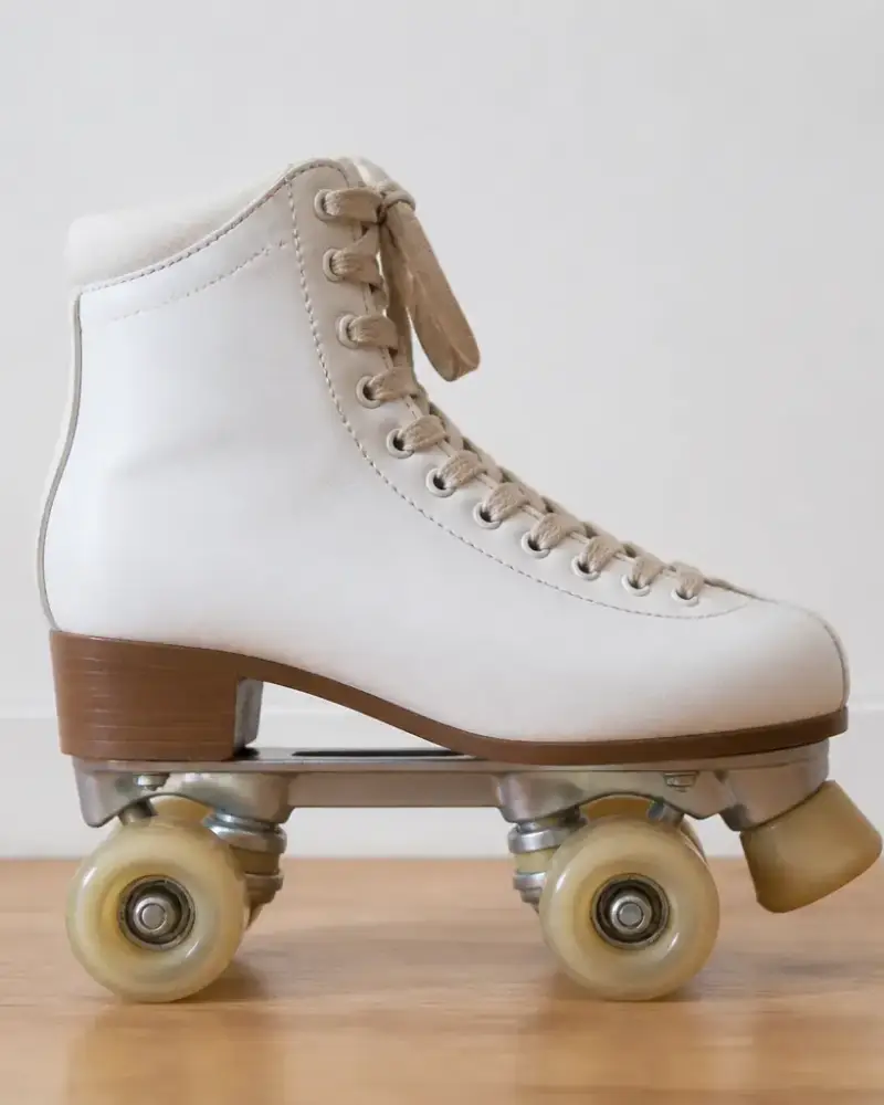 Patin à roulettes quad vu de profil sur un parquet clair, botte, platine, deux essieux et quatre roues bien visibles
