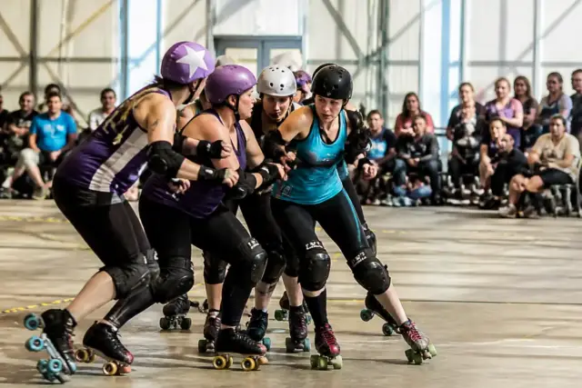 Match intense de roller derby en France avec joueuses en pleine action sur piste intérieure